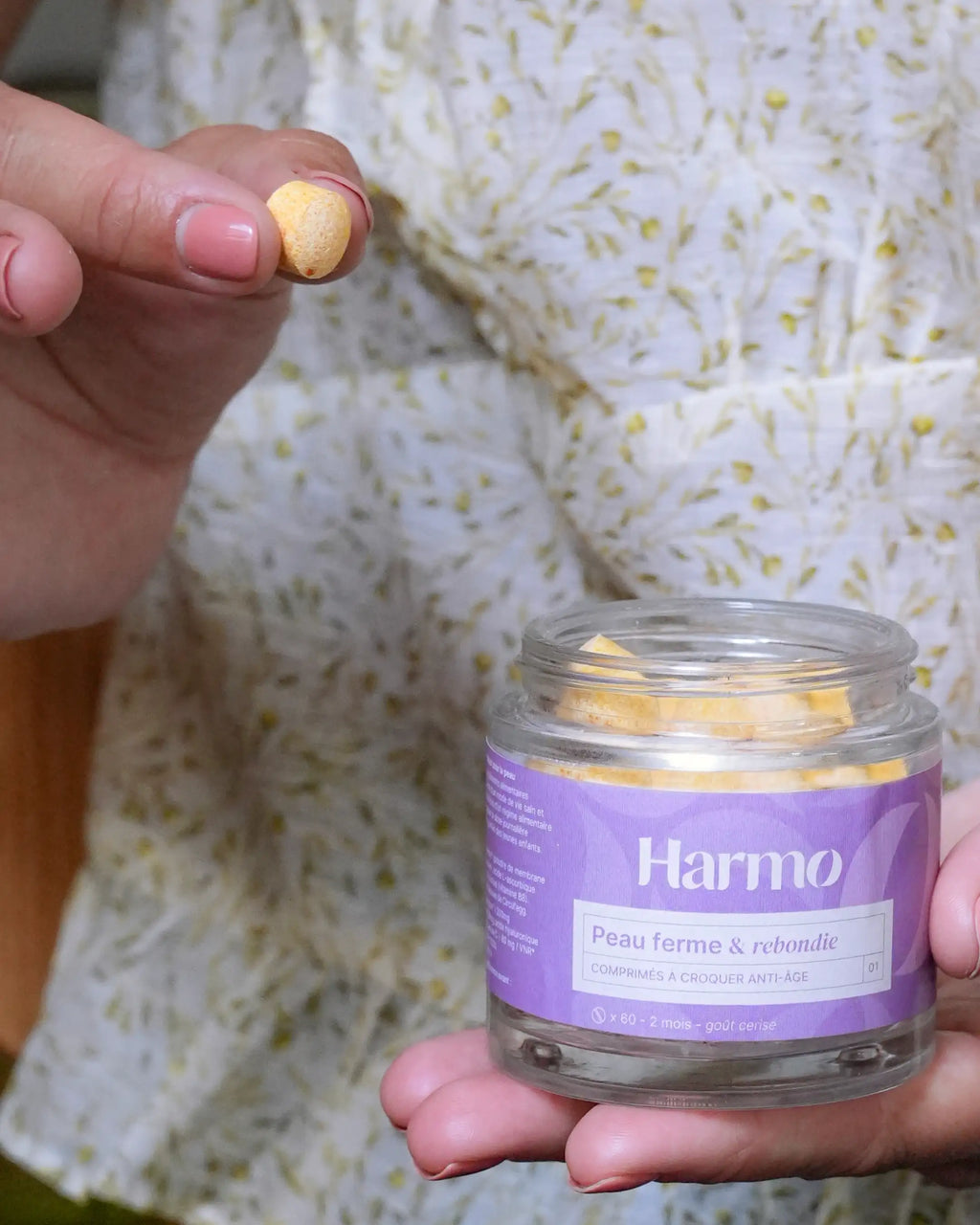 Pot de comprimés à croquer Harmo Anti-âge Peau ferme et rebondie tenu dans la main, présentation de la forme et taille du comprimé